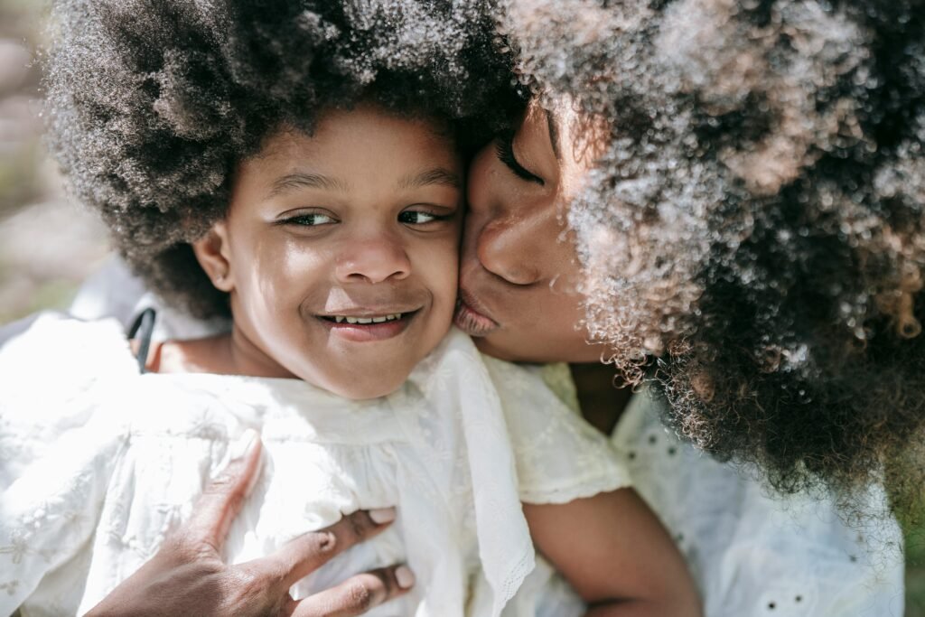 Affectionate moment between a mother and daughter with afro hair, embracing love and happiness.